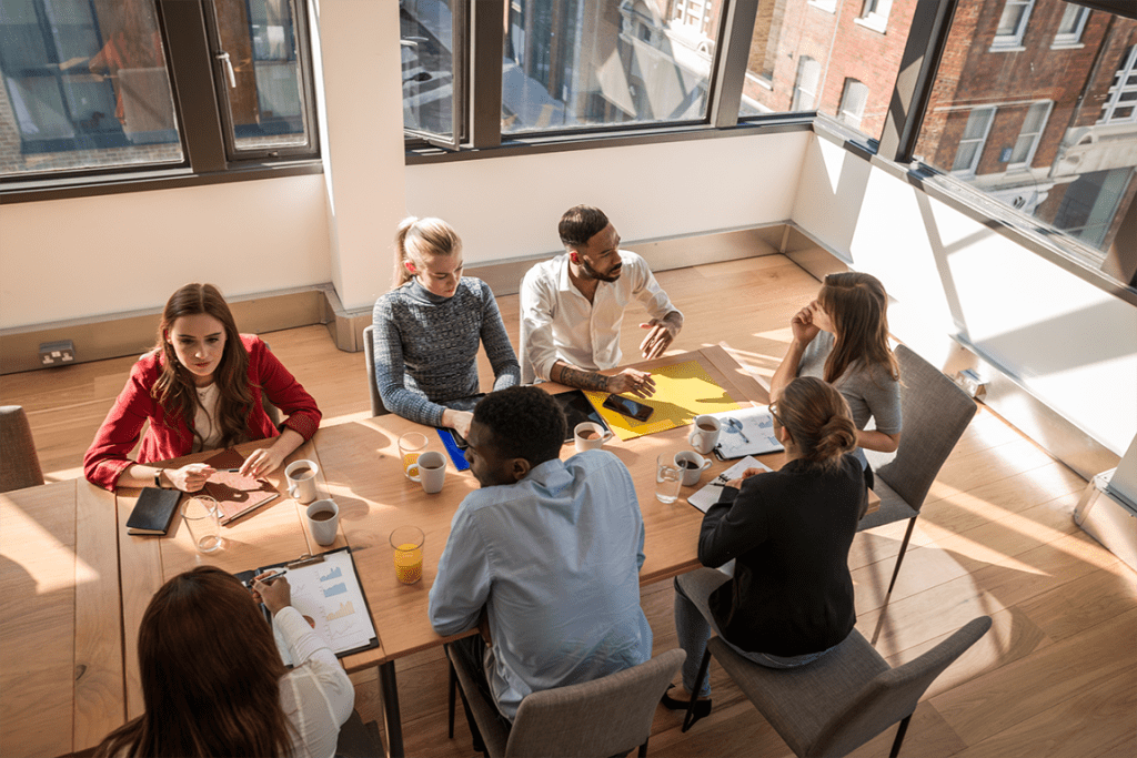 birds eye view of a group of mutli-racial professionals working together at a table in a sunny office room